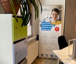 Co-Working-Raum mit Regalen und Tisch.