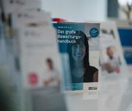 Informationsmaterial und Flyer stehen auf einem Tisch.