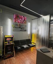 Warteraum mit schwarzen Sitzbänken farbigem Arcade Automat Pflanzen grauen Wänden und Kunstwerken im modernen Stil.