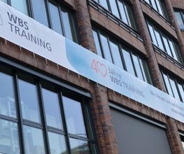Eine Hausfassade an der ein Banner mit der Aufschrift „40 Jahre WBS TRAINING“ angebracht ist.