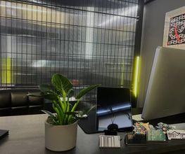 Rezeption im OMEN Tattoo Lab Friedrichshain Berlin. Moderner Empfangsbereich mit Metallgittern, Pflanzen und urbanem Design für Beratung und Walk-ins.