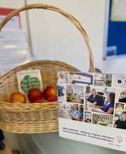 Bio-Obstkorb und Aufsteller mit Fotocollage von Teilnehmer:innen und Mitarbeiter:innen.