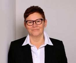Portrait der Teamassistentin Claudi Michel. Eine Frau mit kurzen, braunen Haaren und Brille, die freundlich in die Kamera schaut.