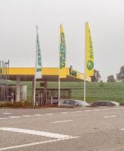 AGROLA Tankstelle in Ettiswil mit TopShop. Strasse im Vordergrund . Mittig drei grosse Fahnen - Landi, TopShop und AGROLA Fahnen. Dahinter AGROLA und TopShop.