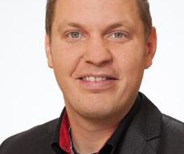Mann mit einem schwarzen Sakko schaut freundlich in die Kamera.