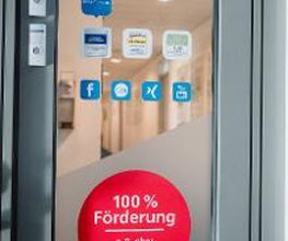 Tür mit einem runden Aufkleber mit der Aufschrift "100 % Förderung"