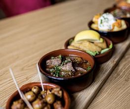 Auswahl kleiner Tapas-Schälchen auf dem Holztisch der Tapas Bar Léon. "Oma's Brett".