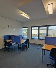 Schulungsraum mit mehreren Arbeitsplätzen mit blauen Trennwänden und Bürostühlen