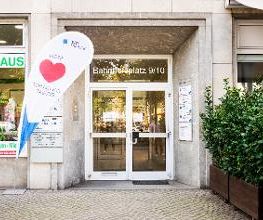 Eingangstür von außen mit Fahnenständer auf dem ein großes rotes Herz und die Aufschrift unser Herz schlägt für Bildung zu sehen ist.