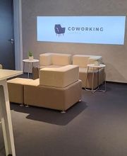 Aufenthaltsbereich mit Sofas und Tischen. Über einen Beamer wird ein Bild an die Wand geworfen, auf dem "Coworking" steht.