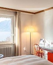 Hotel Albergo Carcani by Ketty & Tommy in Ascona – Doppelzimmer mit rotem Schreibtisch und Seeblick auf den Lago Maggiore