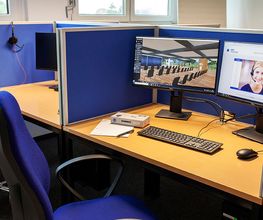 Arbeitsplatz mit zwei Bildschirmen, Tastatur und Maus sowie blaue Trennwände.