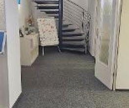 Flur der zu einer Wendeltreppe führt. Daneben ein Regal, rechts eine Tür.
