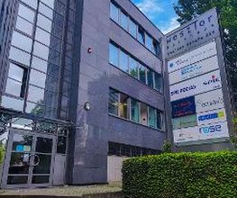 eine Gläserne Haupteingangstür, links Beschilderung WBS TRAINING AG und weitere Firmen.