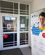 Eingangsbereich mit Glastür und einem Roll Up Banner.