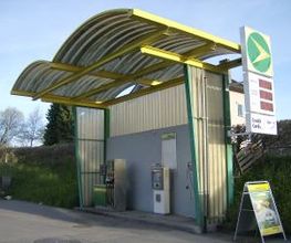 AGROLA Tankstelle in Uznach mit geschwungener Überdachung. Rechts ein Stellschild darüber AGROLA Logo und digitale Preisanzeige. Eine Tanksäule und ein Zahlterminal