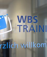 Eingangstür aus Glas im Treppenhaus mit der Aufschrift WBS TRAINING. Herzlich Willkommen.