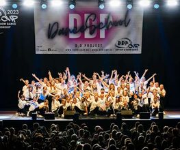 D.D.Project - Hip-Hop Tanzschule Dresden Gruppenfoto einer Tanzformation auf einer Wettbewerbsbühne mit starker Bühnenbeleuchtung und begeistertem Publikum.