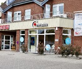 Außenansicht gesamt mit dem Restaurant links und den Hinweisschildern der anderen Mieter.