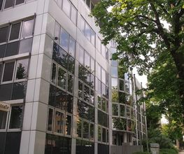 modernes Gebäude mit Fenstern neben einem grünen Baum.