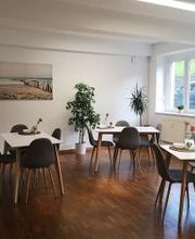 Aufenthaltsraum mit mehreren Tischen und Stühlen.