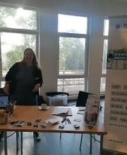 Eine fröhliche Frau steht am Infostand im Jobcenter