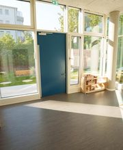Großer Gruppenraum mit breiten Fensterflächen, Blick in den Garten, Bücherregal und niedrigem Spiel- und Sitzbereich aus Holz.
Fröbel-Kindergarten Essener Straße, Hamburg, © Fröbel, Foto: Martin Arnold. Alle Rechte vorbehalten.