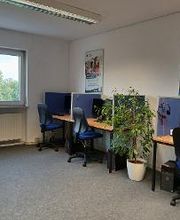 Drei Schreibtische mit Schreibtischstuhl, blaueen Trennwänden, Bildschirmen, Tastatur und Headset.