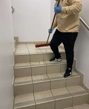 E&E Gebäudereinigung Gründliche Treppenreinigung, bei der eine Fachkraft mit Besen losen Schmutz und Ablagerungen entfernt, um ein sauberes und sicheres Treppenhaus zu gewährleisten.