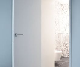 Einblicke in ein durchdachtes Raumkonzept: Die geöffnete, wandbündig integrierte Tür gibt den Blick frei auf ein modernes Bad mit Mosaikfliesen und wandhängendem WC. Die klare Linienführung, die reduzierte Farbgebung und die hochwertigen Materialien unterstreichen den minimalistischen Charakter des Entwurfs.