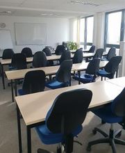 Schulungsraum für Präsenzkurse, viele Tische in einer Reihe mit Stühlen