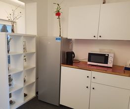 Küchenzeile eines Aufenthaltsraumes mit Regal, Kühlschrank, Wasserkocher und Mikrowelle.