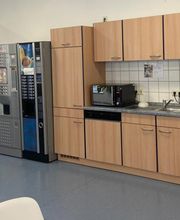 Helle, voll ausgestattete Teilnehmerküche mit Getränkeautomaten und Mikrowelle.