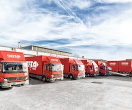 DELTA Logistik LKW-Flotte auf Firmengelände mit mehreren roten Transportern