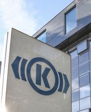 The photo shows the Knorr-Bremse building in Munich, where the management of the two divisions Commercial Vehicle Systems and Rail Vehicle Systems is based. In the foreground is a large entrance sign with the Knorr-Bremse logo.