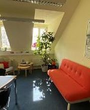 Ein Pausenbereich mit rotem Sofa, einem Tisch und Tischpflanzen.