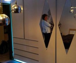 ..Kleiderschrank in weiss Hochglanz mit Griffleisten in Aluminium und ringsum LED Lichttechnik..