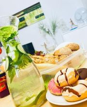 Eine Karaffe mit Wasser, Minze und Limetten. Daneben ein Teller mit Donuts und eine Schüssel mit Baguettes.