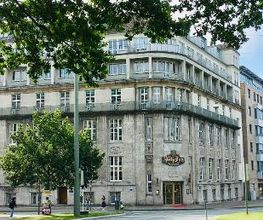 Das Außengebäude der WBS TRAINING (und anderen Unternehmen) als Eckansicht vom Willy Brandt Platz her fotografiert. Schönes, altes Gebäude, grauer Stein, große Fenster, Balkone in den oberen Etagen.