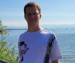 Ein Mann mit weißem Shirt an einem See.