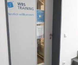 Eine Eingangstür zum Standort mit der Aufschrift "WBS TRAINING. Herzlich willkommen"