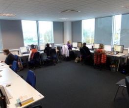 Schulungsraum mit PC-Arbeitsplätzen. Mehrere Teilnehmer werden gerade unterrichtet.