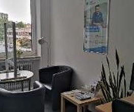 Ein Beratungsbüro mit einem Arbeitsplatz, einem runden Tisch und drei Sesseln