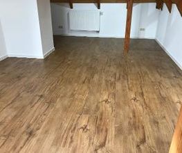 In dieser Dachgeschosswohnung haben wir einen Design-Belag in rustikaler Eichenoptik von Amtico verlegt und anschließend weiße Sockelleisten angebracht.