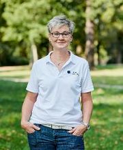 Frau mit Brille im weißen Polohemd, auf das das WBS TRAINING Logo gestickt ist.