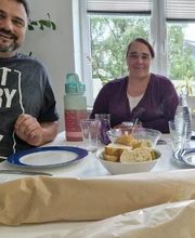 Ein Mann und eine Frau sitzen an einem gedeckten Tisch. Anlass ist die Verabschiedung einer Umschülerin.