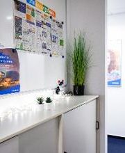 Flur mit einer Informationstafel und einem Sideboard darunter mit mehreren Pflanzen und einer Lichterkette..