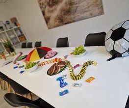 Ein langer Tisch mit Donuts, Süßigkeiten und Weintrauben sowie Fußballdekoration zum Anlass der EM.