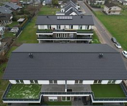 Luftbild eines fertigen Mehrfamilienhauses mit Balkonen und begrünten Terrassen. Ein Projekt von AS-Bau.