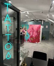 Empfangs- und Wartebereich im OMEN Tattoo Studio Berlin Mitte mit Galerie-Flair, heller Einrichtung und stilvollem Neon-Schriftzug.